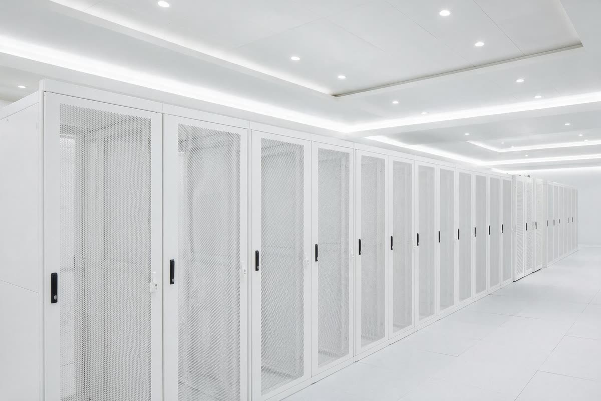 An existing row of white server cabinets extended by newer cabinets at the far end of the row.